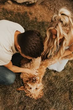 a man and woman petting a dog on the grass