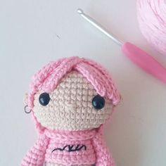 a crocheted doll is next to a ball of yarn