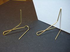 two pairs of gold earrings sitting on top of a black table next to a white card