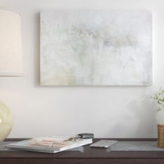 a painting is hanging on the wall above a table with a lamp and cell phone