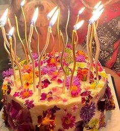 a woman blowing out candles on a cake with pink and yellow flowers in the foreground