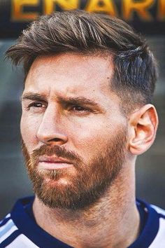 a close up of a man with a beard wearing a soccer jersey and looking at the camera