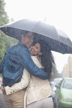 two people hugging under an umbrella in the rain