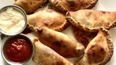 several pastries on a plate with dipping sauces