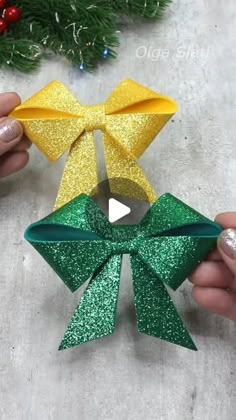 someone is holding two christmas bows in their hands, one yellow and the other green