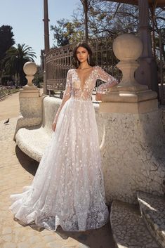 a woman standing in front of a gazebo wearing a wedding dress with long sleeves