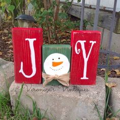 a snowman made out of wood blocks with the word joy spelled in red and green