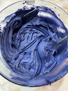 a bowl filled with blue icing on top of a table