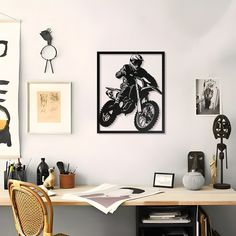 a desk with a chair and pictures on the wall above it in a home office