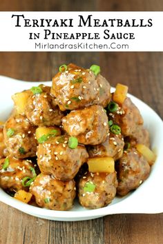 a white bowl filled with meatballs and pineapple sauce on top of a wooden table