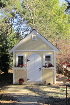 a small white shed sitting in the middle of a forest