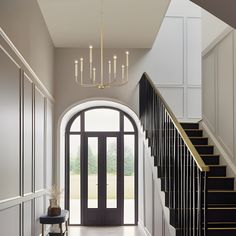 an entryway with stairs and chandelier in the center, leading to a foyer