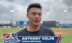 a man standing on top of a baseball field next to a sign that says anthony volpe