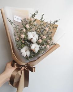 a bouquet of cotton and greenery wrapped in brown paper