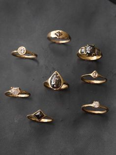 six different types of rings sitting on top of a black surface with one diamond in the middle