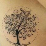 a woman's back with a tree tattoo on it