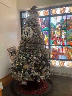 a decorated christmas tree in front of a stained glass window