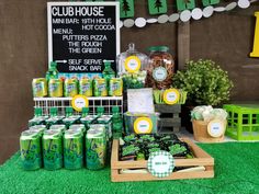 a table topped with lots of green drinks and desserts next to a chalk board