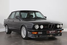 a black bmw is parked in a white room