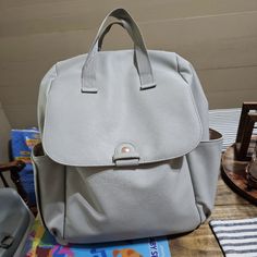 a gray purse sitting on top of a wooden table