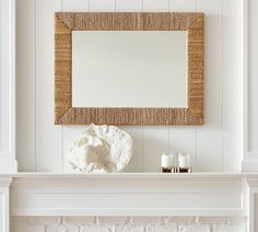 a white fireplace with a mirror above it