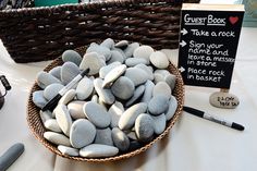 a basket filled with rocks next to a sign that says guest book and some pens