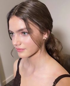 a young woman is sitting in a chair with her hair pulled back and wearing earrings