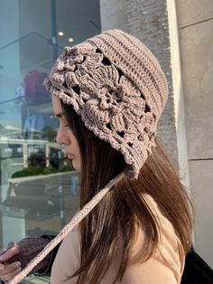 a woman is wearing a crocheted hat while looking at her cell phone outside