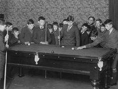 a group of men standing around a pool table