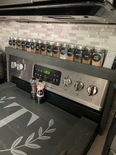 a stove top oven sitting inside of a kitchen next to a counter with spices on it