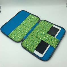 an open laptop case sitting on top of a white table next to a cell phone