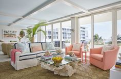 a living room filled with lots of furniture next to tall windows covered in glass doors