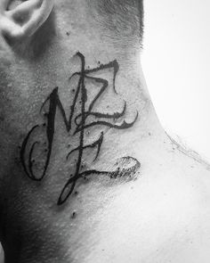 a man with a tattoo on his neck has the letter m in cursive writing