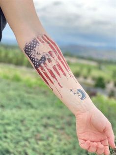 a person's arm with an american flag tattoo on it and the moon in the sky