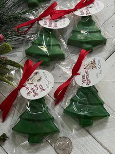 small christmas trees are wrapped in plastic and tied with red ribbon, sitting next to a quarter penny