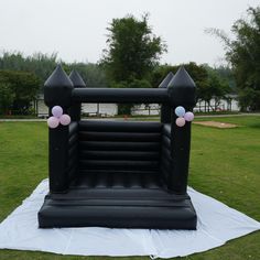 an inflatable arch with balloons is on the ground near some grass and trees