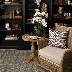 a living room filled with furniture and bookshelves next to a vase full of flowers