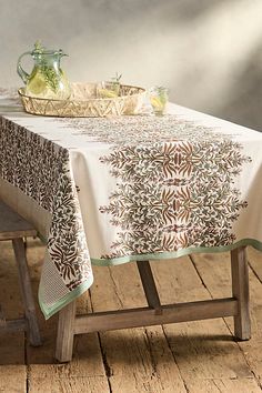 a table with a white and brown table cloth on it next to a wooden bench