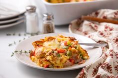 a white plate topped with an omelet covered in meat and veggies