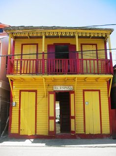 a yellow building with red trim and balconies