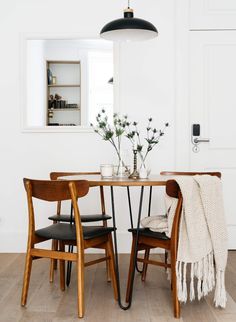 a dining room table with two chairs and a rug on the floor next to it