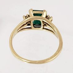 "This magnificent vintage ring boasts a lovely emerald and two diamonds set in 18K yellow gold. The emerald has a rich bluish-green color and weighs in at 1 1/4 carats. An accent diamond is set on each side of the emerald, adding elegance and sparkle. The ring has triple branched shoulders that add interest beyond the classic shank. Luxurious! Vintage: 1990s Size: 6 Materials: 18K Yellow Gold, Emerald, Diamonds Marked: 18K Emerald: 7 mm x 7mm x 4.4mm, approx. 1.25 ct. 2 Diamonds: brilliant cut, Gold And Emerald Ring, Emerald Ring With Diamonds, Gold And Emerald, Bluish Green, Multi Stone Ring, Vintage Ring, Multi Stone, Emerald Ring, 10k Gold