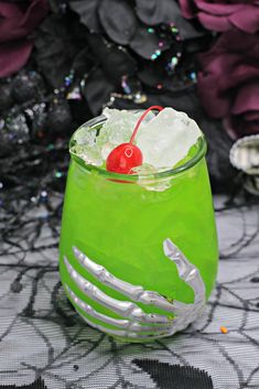 a green cocktail with a cherry on the rim and garnished in silver foil