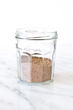 a glass jar filled with spices on top of a marble counter