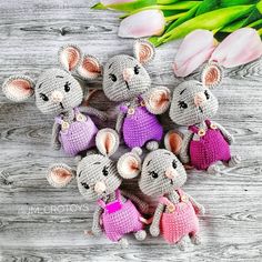 small crocheted mouses with pink and purple outfits, sitting next to tulips