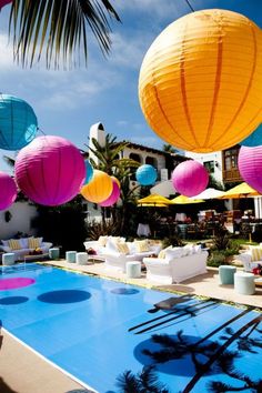 an outdoor swimming pool with paper lanterns hanging from it's ceiling and lounge chairs around it