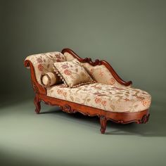 an antique style chaise lounge with pillows on it's arms and back rests against a green background