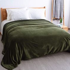 a bed with a green blanket and white pillows