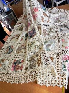 a crocheted table cloth with flowers on it sitting on top of a wooden table