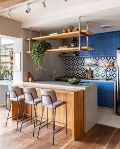 a kitchen with blue cabinets and white counter tops next to an island in front of a refrigerator